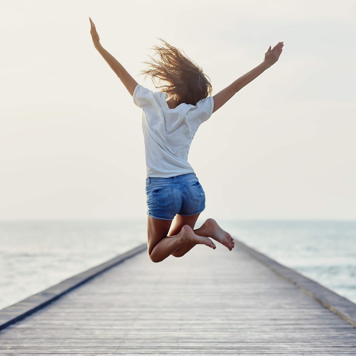 Lady jumping on a pier